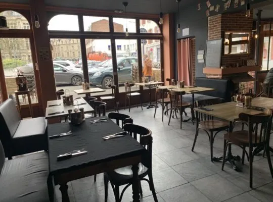 La salle du restaurant, tables dressées devant les grandes baies vitrées.